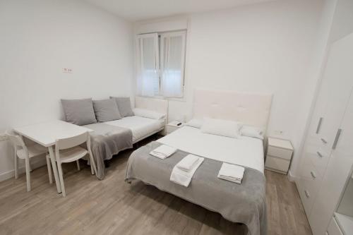 a room with two beds and a table and a couch at Pension MD in San Sebastián