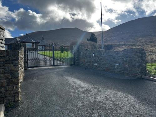a stone fence with a gate in front of a house at Atlantic Sea View in Tralee