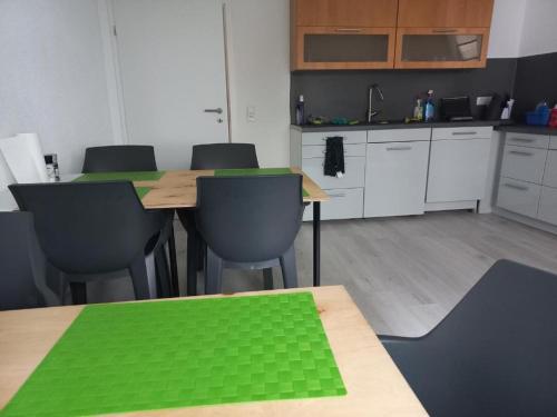 a kitchen with tables and chairs with green covers at hoteliving am Bahnhof in Pohlheim