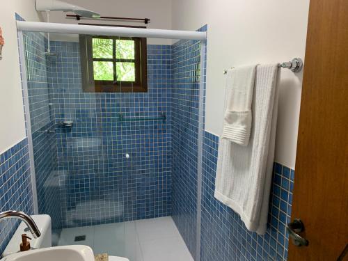 y baño de azulejos azules con ducha y lavamanos. en Casa Oásis: Requinte, Paz e Conforto na Natureza, en Atibaia