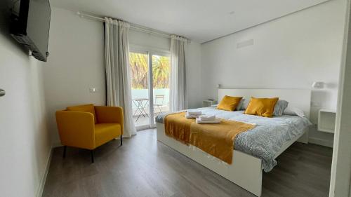 een slaapkamer met een bed en een gele stoel bij En el Casco Histórico in La Laguna