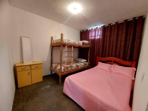 a bedroom with a bunk bed and a dresser at Casa inteira no centro de São Thomé das letras in São Thomé das Letras