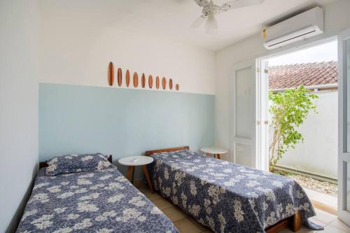 two beds in a room with a window at Chalé Aconchegante na Praia da Tabatinga in Caraguatatuba