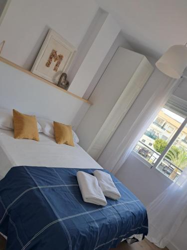 um quarto com uma cama com lençóis azuis e uma janela em EL PEÑÓN IDÍLICO PISO A PIE DE Playa em Salobreña