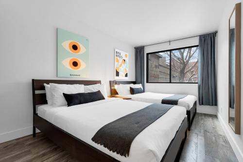 duas camas num quarto de hotel com uma janela em Liv MTL Urban em Montreal
