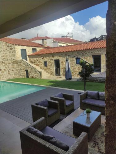 a patio with chairs and an umbrella and a pool at Casa do Caseiro in Outeiro Maior
