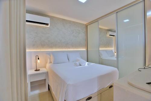 a white bedroom with a white bed and a mirror at Belíssimo Flat no Lake Side - Beira Lago in Brasilia