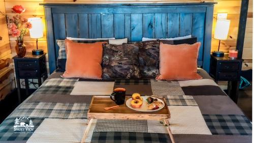 a bed with a tray with a plate of food on it at Modern Luxury-6 Bed 5 Bath CABIN AMAZING LOCATION & PRIVACY! -4 Miles to Gatlinburg-7 to Dollywood-Hot Tub-Fireplace-King Suits-Theater-Grill-Free Parking for 10 Vehicles-Fire pit-Fully Stocked Kitchen-"Smoky View Cabin" in Sevierville