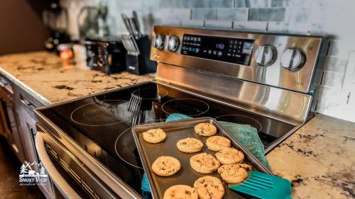 a pan of cookies sitting on top of a stove at Modern Luxury-6 Bed 5 Bath CABIN AMAZING LOCATION & PRIVACY! -4 Miles to Gatlinburg-7 to Dollywood-Hot Tub-Fireplace-King Suits-Theater-Grill-Free Parking for 10 Vehicles-Fire pit-Fully Stocked Kitchen-"Smoky View Cabin" in Sevierville