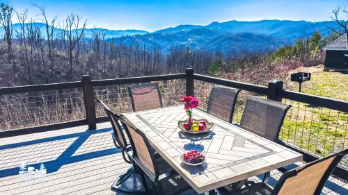 a table on a deck with a view of the mountains at Modern Luxury-6 Bed 5 Bath CABIN AMAZING LOCATION & PRIVACY! -4 Miles to Gatlinburg-7 to Dollywood-Hot Tub-Fireplace-King Suits-Theater-Grill-Free Parking for 10 Vehicles-Fire pit-Fully Stocked Kitchen-"Smoky View Cabin" in Sevierville