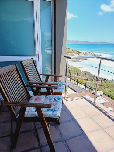 a pair of chairs sitting on a balcony overlooking the ocean at Langebaan Beach Towers in Langebaan