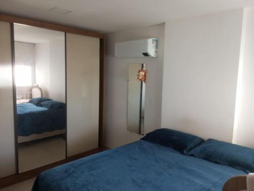 a bedroom with a mirror and a blue bed at Apart° Grande Lar in Guarapari