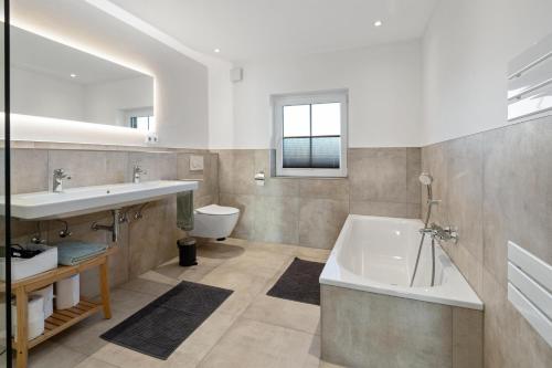 ein Badezimmer mit einer Badewanne, einem Waschbecken und einem WC in der Unterkunft Ferienwohnung Rettbrook in Bad Zwischenahn