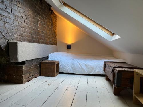 a bedroom with a bed and a brick wall at Lofty split-level period flat in Highbury in London