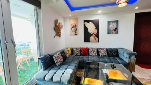 a living room with a blue couch and a glass table at Gold Crest Luxurious Apartments DHA Lahore by LMY in Lahore