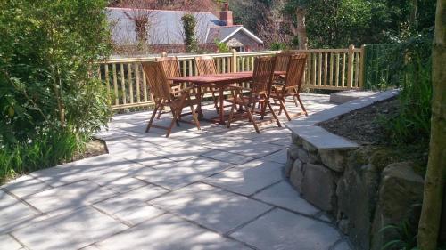 a patio with chairs and a table and a fence at Penbryn Mynach Holiday Cottage in Barmouth