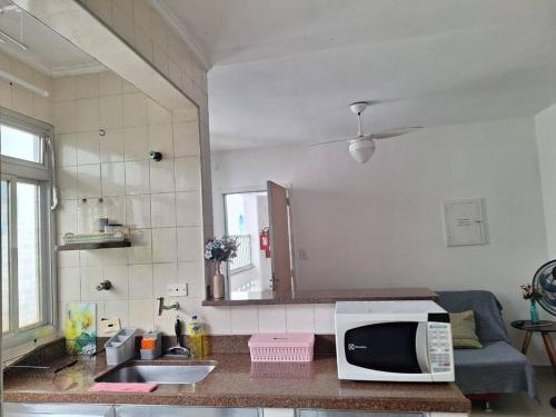 eine Küche mit einer Spüle und einer Mikrowelle auf der Theke in der Unterkunft Apto a dois quarteirões da praia da Enseada in Guarujá