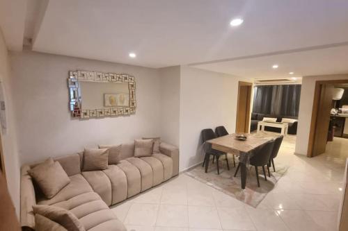 een woonkamer met een grote bank en een tafel bij Appart familial chic & confort in Kenitra