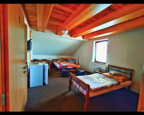a bedroom with two beds in a room with a wooden ceiling at Penzion Nové dvory in Kutná Hora