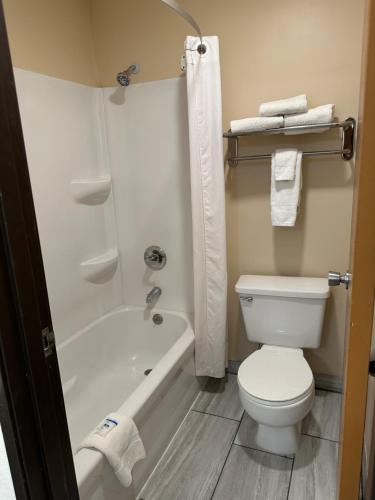 a bathroom with a white toilet and a bath tub at Super 8 by Wyndham Grand Island in Grand Island