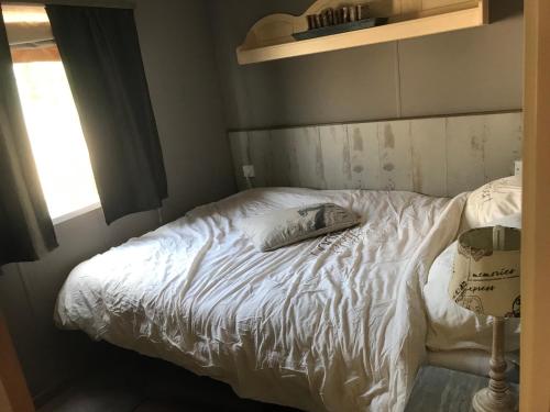 un letto con lenzuola bianche e un cuscino sopra di Stacaravan aan de Maas a Op-Andel