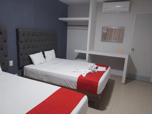 a bedroom with two beds with red and white sheets at Hotel MCH in Veracruz