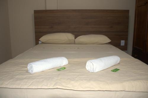 een bed met 2 opgerolde handdoeken en 2 slippers bij Pé da Serra Hotel in Resende