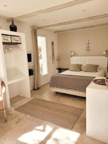 a white bedroom with a bed and a window at La maison blanche Intra-Muros Free parking in Aigues-Mortes