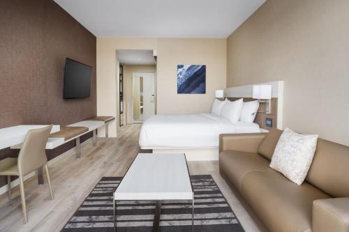 a hotel room with a bed and a couch at AC Hotel by Marriott Jacksonville St Johns Town Center in Jacksonville