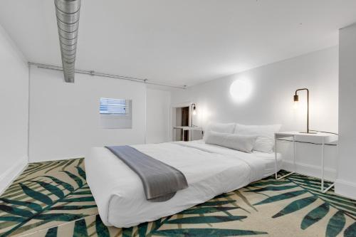 a white bedroom with a large bed and a rug at LiV MTL Main in Montréal