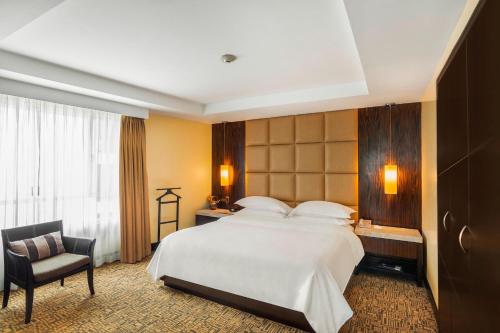 a hotel room with a large bed and a chair at Sheraton Guayaquil in Guayaquil