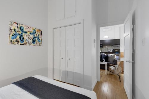 a white bedroom with a bed and a living room at LiV MTL Main in Montréal