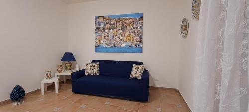 a blue chair in a living room with a painting on the wall at La Casa sulla Piazza in Sciacca