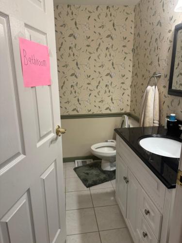 baño con aseo y lavabo con letrero rosa en 楼上次卧.独立卫生间, en Gaithersburg