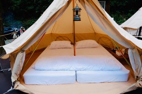 ein Bett in einem Zelt mit einer Lampe darüber in der Unterkunft The camp Maekampong in Ban Pok Nai