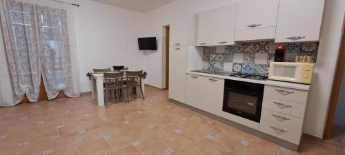 a kitchen with white cabinets and a table with a microwave at La Casa sulla Piazza in Sciacca