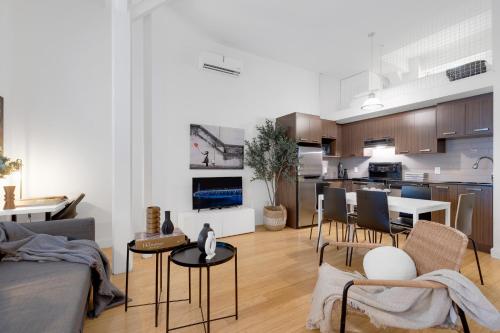 a living room with a couch and chairs and a kitchen at LiV MTL Main in Montréal