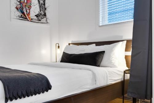 a bedroom with a bed with white sheets and a window at LiV MTL Main in Montréal