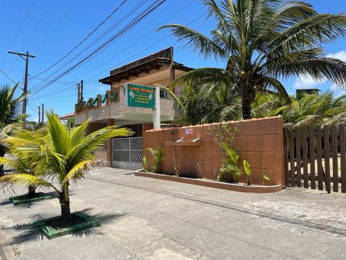 a building with palm trees in front of a fence at Long Island in Ilha Comprida