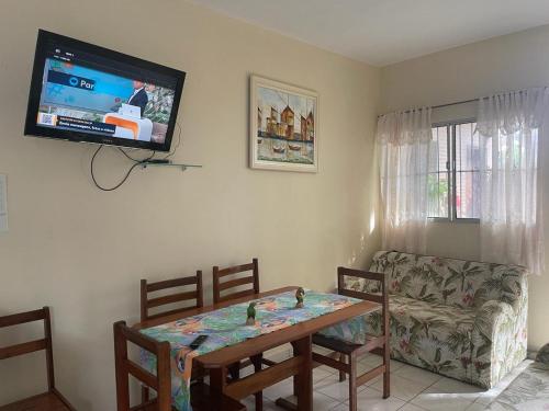 a living room with a table and a tv on the wall at Long Island in Ilha Comprida