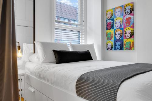 a white bedroom with a large white bed and a window at LiV MTL Main in Montréal