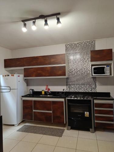 a kitchen with a stove and a white refrigerator at Casa Temporada peterle Iriri in Iriri