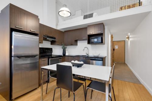 a kitchen with a white table and a stainless steel refrigerator at LiV MTL Main in Montréal