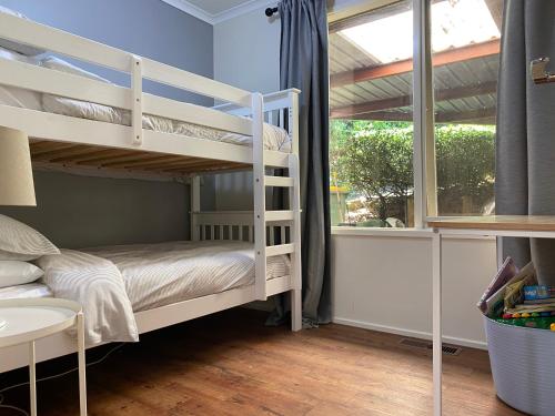 a bedroom with bunk beds and a window at Cockatoo Rainforest Escape in Cockatoo