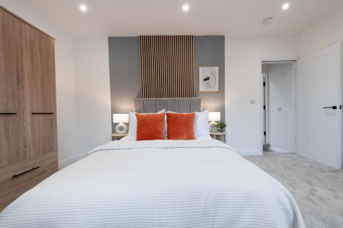 1 dormitorio con 1 cama blanca grande con almohadas de color naranja en Aviary Nest by Nordstay, en Amley
