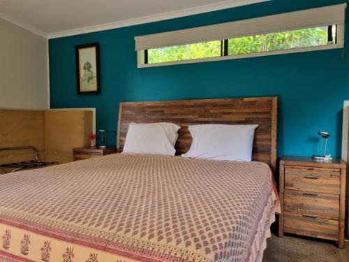 1 dormitorio con cama y pared azul en Wompoo Eco Retreat, en Cow Bay