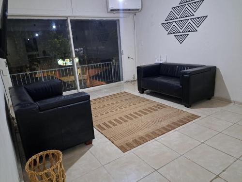 una sala de estar con 2 sofás negros y una alfombra en Casona con Barbacoa en Av princ, en Montevideo