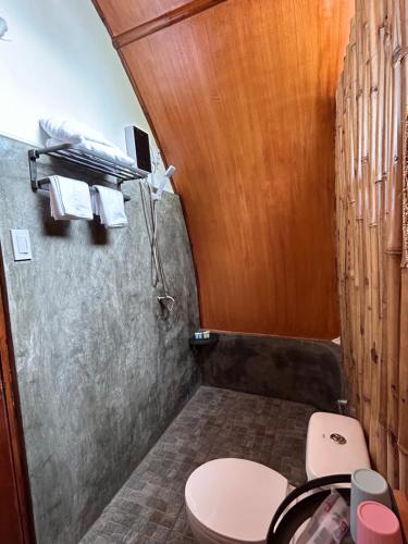a bathroom with a toilet and a wooden wall at East Holiday Resort Moalboal in Moalboal