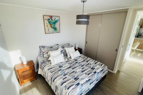 a bedroom with a bed with pillows and a table at Departamento completo a pasos del mar in La Serena
