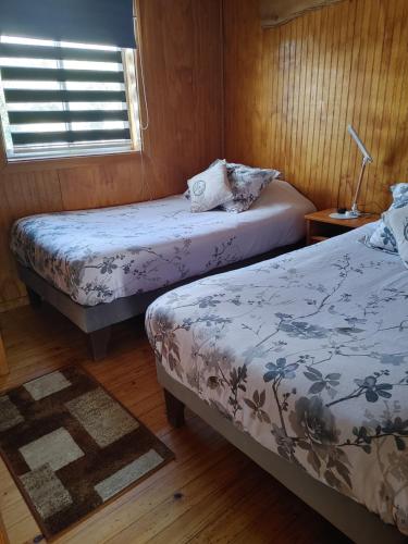 a room with two beds and a window at Ruta Austral - Coyhaique in Coihaique